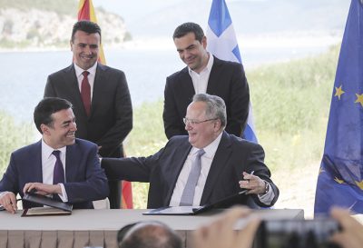 Greek Prime Minister Alexis Tsipras, background right, and his Macedonian counterpart Zoran Zaev, background left, look on as Greek Foreign Minister Nikos Kotzias, right, and his Macedonian counterpart Nikola Dimitrov sign an agreement on Macedonia's new name in the village of Psarades, Prespes Greece, on Sunday, June 17, 2018. The preliminary deal launches a long process that will last several months. If successful, it will end a decades-long dispute between neighbors Greece and Macedonia _ which will be renamed North Macedonia. (AP Photo/Yorgos Karahalis)