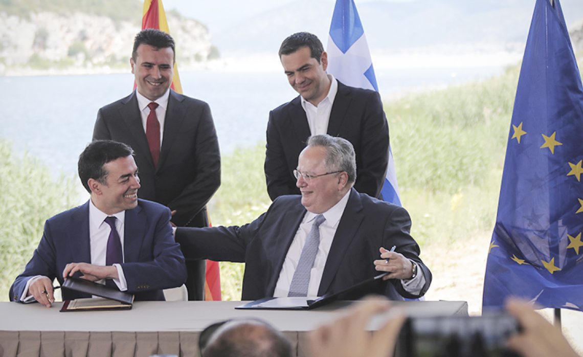Greek Prime Minister Alexis Tsipras, background right, and his Macedonian counterpart Zoran Zaev, background left, look on as Greek Foreign Minister Nikos Kotzias, right, and his Macedonian counterpart Nikola Dimitrov sign an agreement on Macedonia's new name in the village of Psarades, Prespes Greece, on Sunday, June 17, 2018. The preliminary deal launches a long process that will last several months. If successful, it will end a decades-long dispute between neighbors Greece and Macedonia _ which will be renamed North Macedonia. (AP Photo/Yorgos Karahalis)